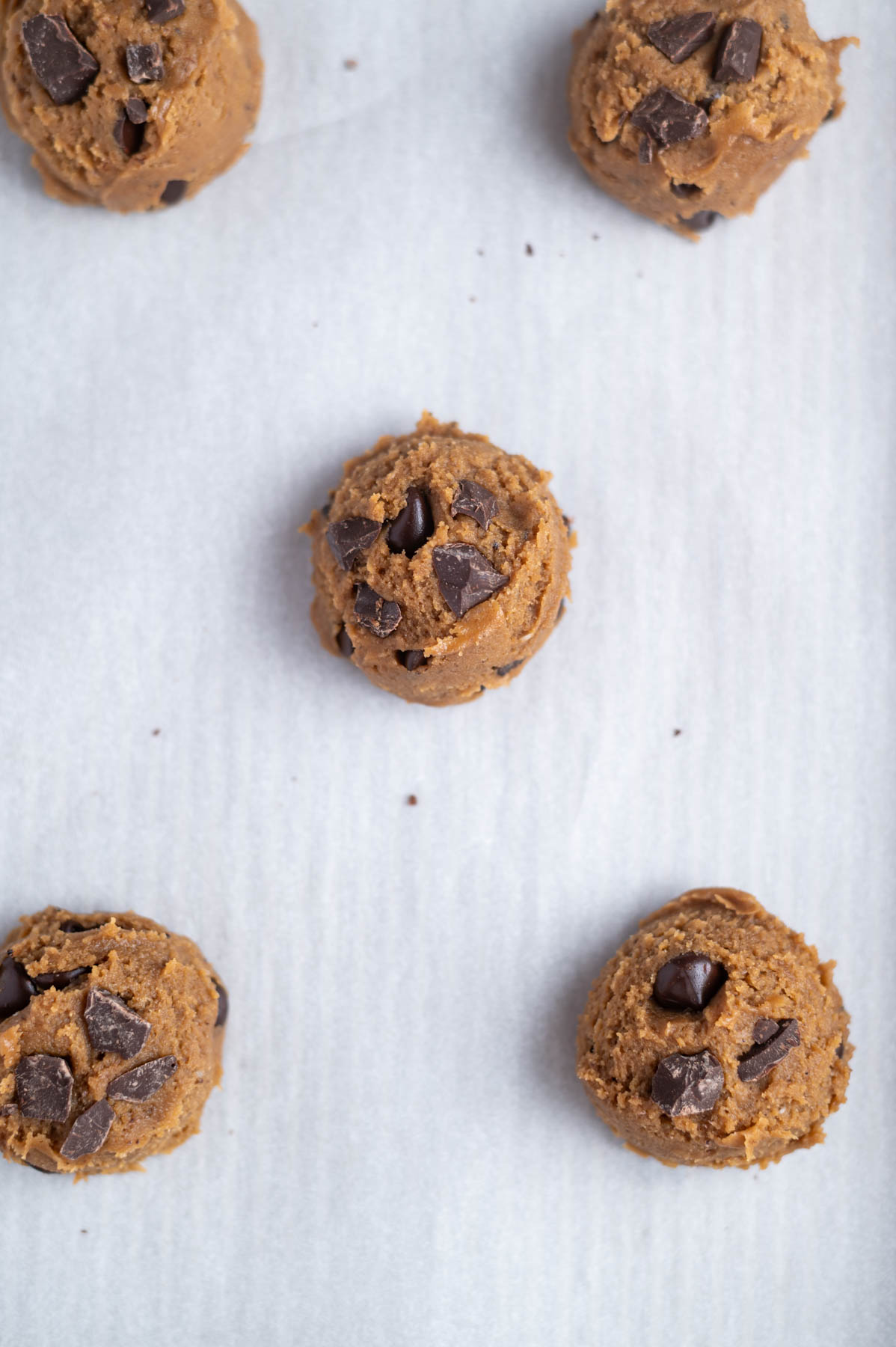 cookie dough on a parchment lined baking sheet with additional chocolate pressed on top