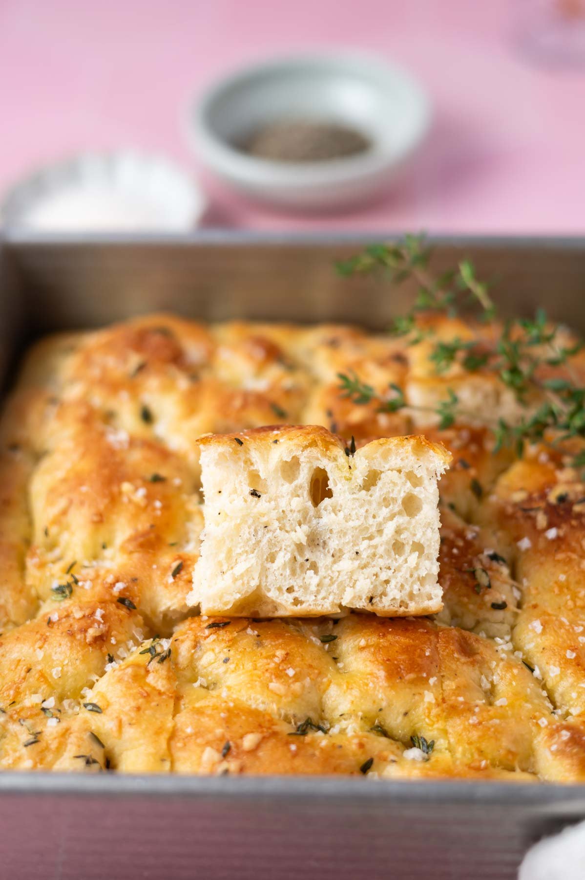 slice of focaccia showing crumb while sitting inside a baking pan