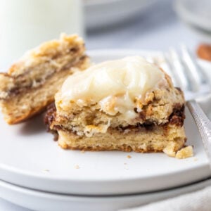 cut biscuit showing cinnamon roll filling on a plate with milk in the background