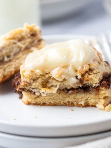 cut biscuit showing cinnamon roll filling on a plate with milk in the background