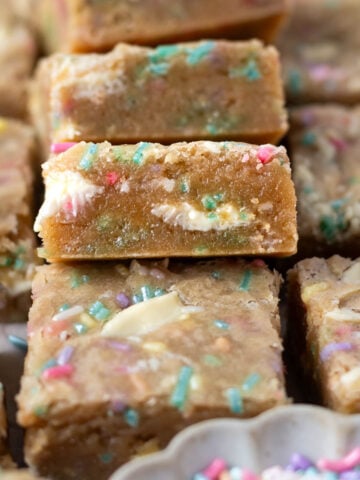 pile of birthday cake blondies showing the soft centers with sprinkles and white chocolate