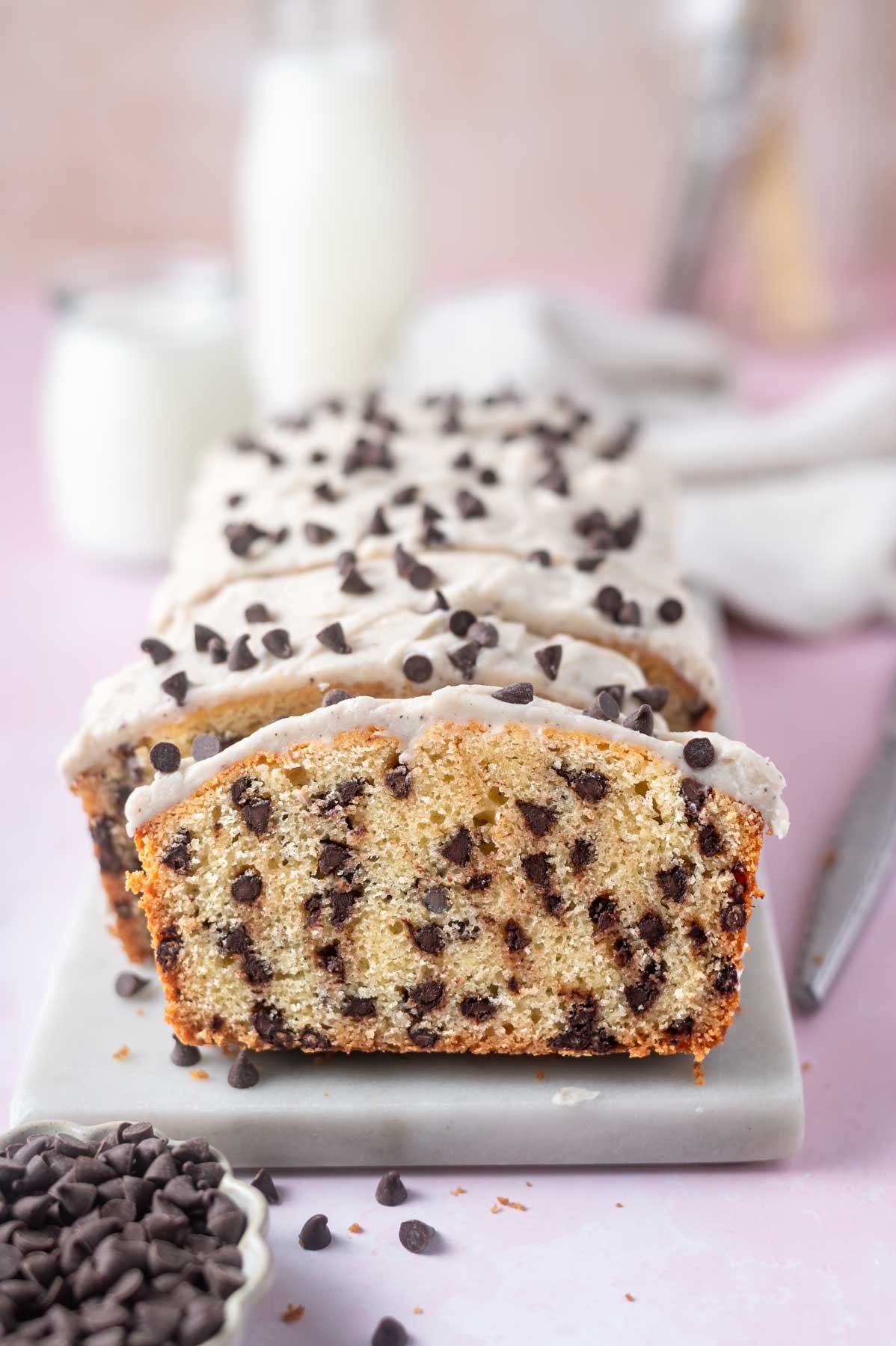 chocolate chip loaf cake slices on a marble board with milk glasses in the background