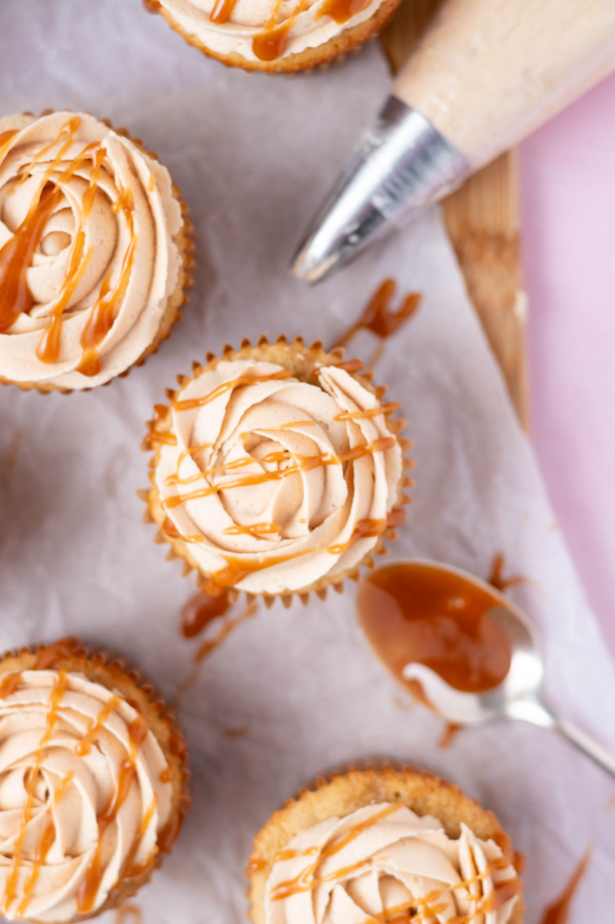 caramel drizzled over the tops of cupcakes set on a parchment lined cutting board