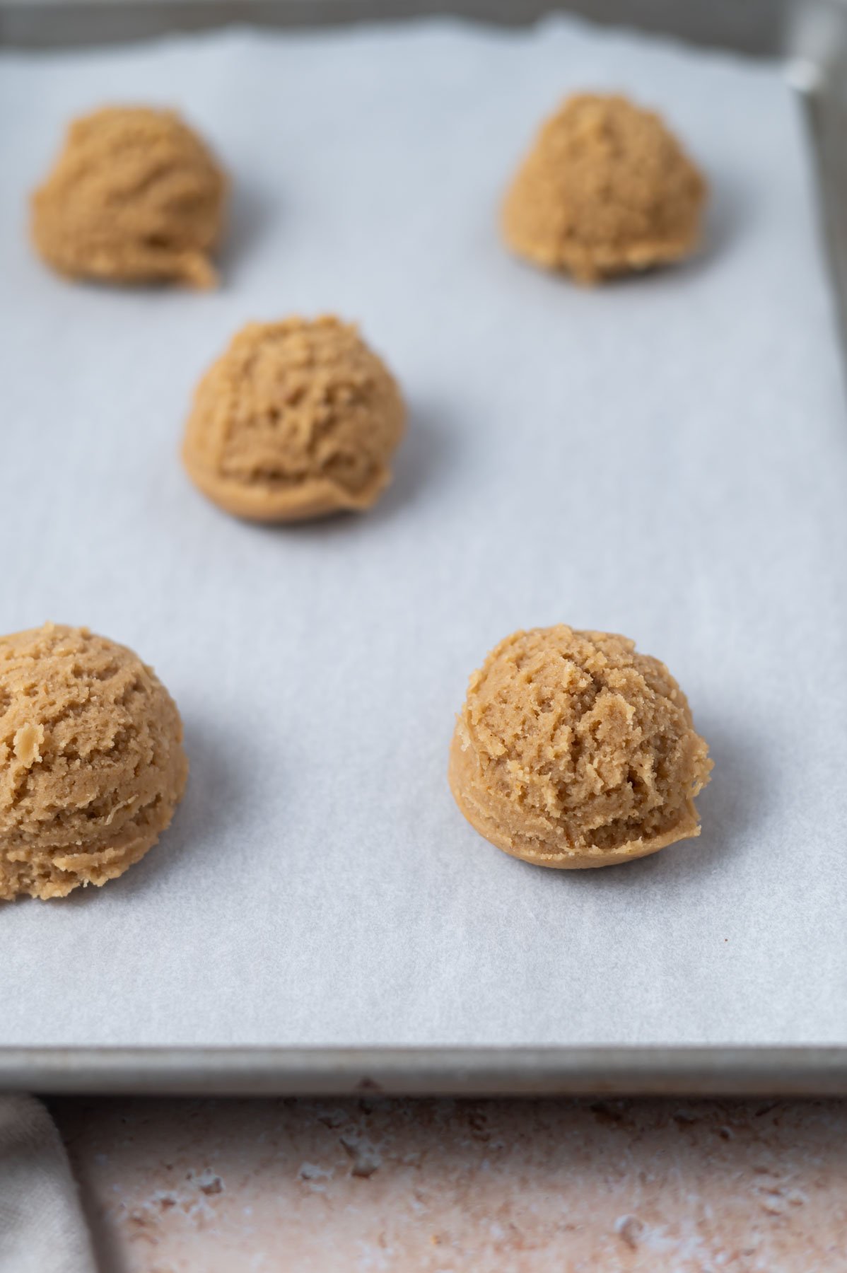 cookie dough portions on a parchment lined baking sheet