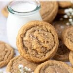 chocolate chipless cookie leaning up against a glass of milk with more cookies piled around and text overlay