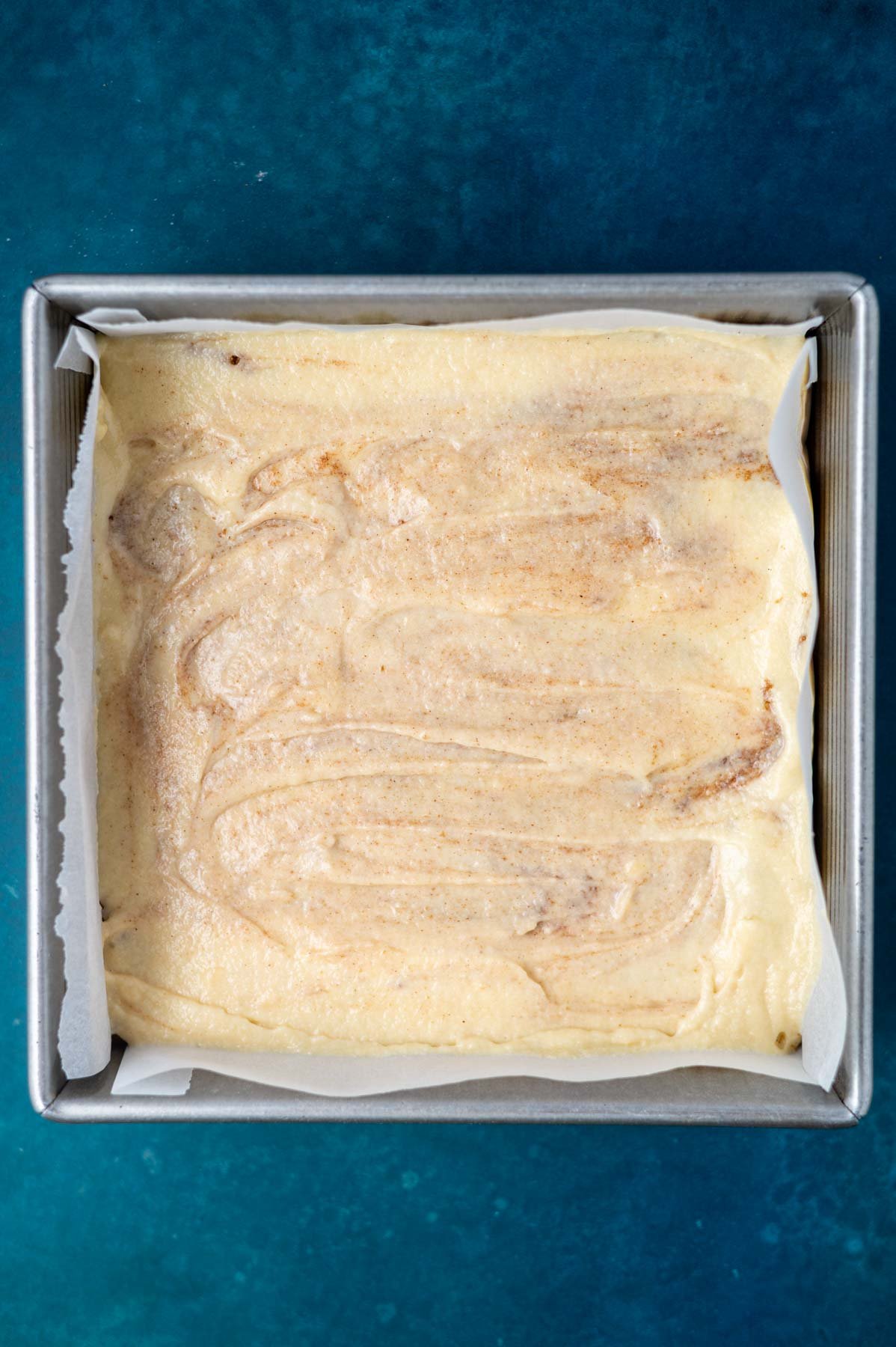 cinnamon swirled cake batter in a parchment lined baking pan