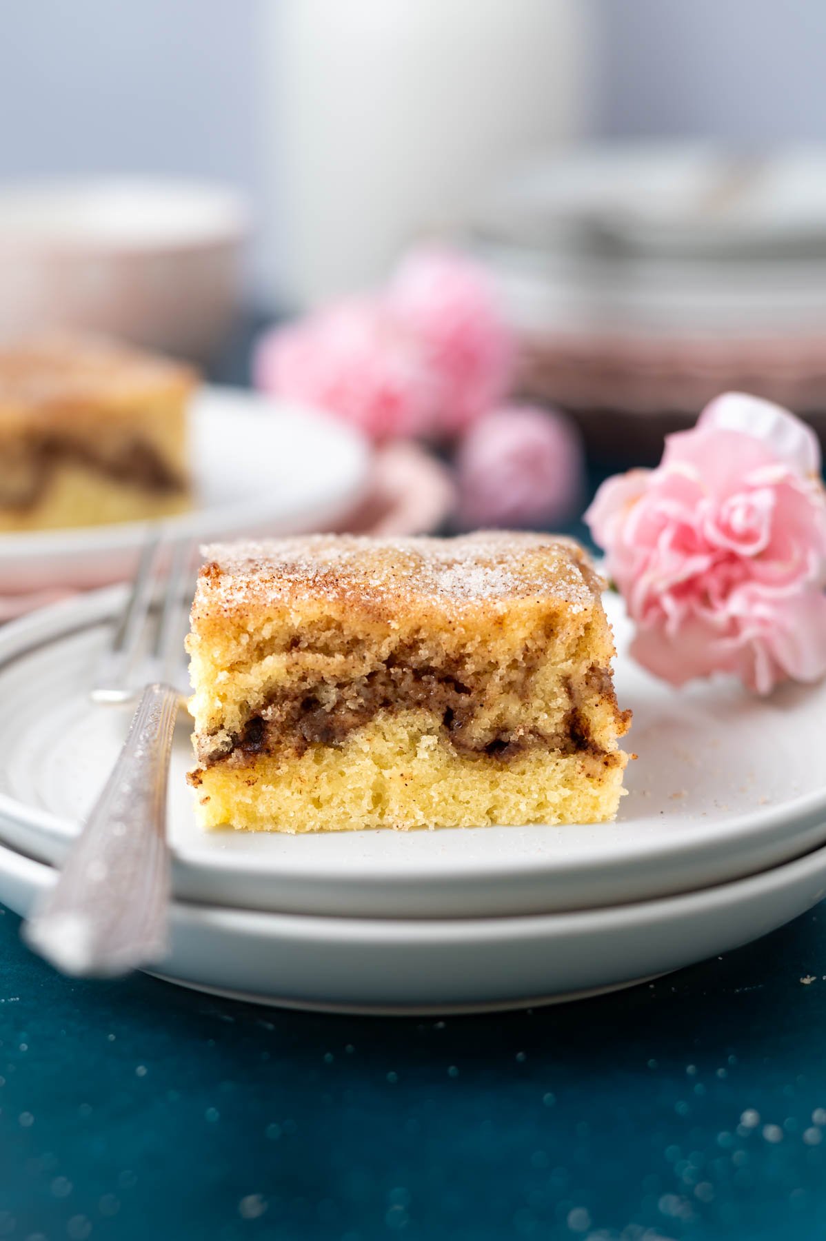 slice of cake on a plate with a fork and a pink flower