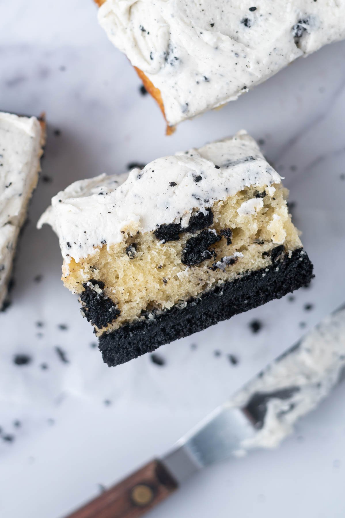 slice of cookies and cream cake on it's side showing cookie layer, fluffy oreo stuffed vanilla cake and Oreo filling frosting