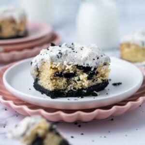 slice of cookies and cream cake on a plate with a piece on a fork and milk in the background