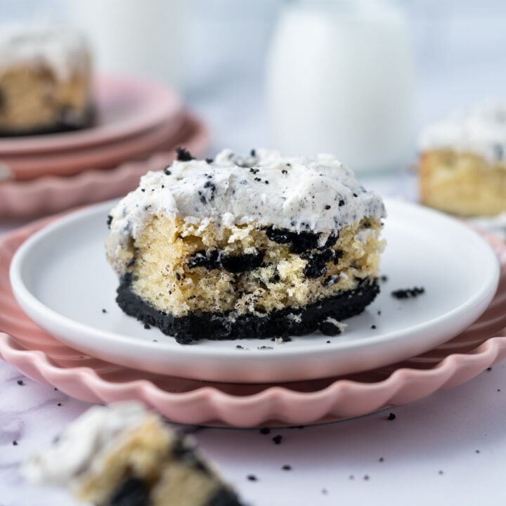 slice of cookies and cream cake on a plate with a piece on a fork and milk in the background