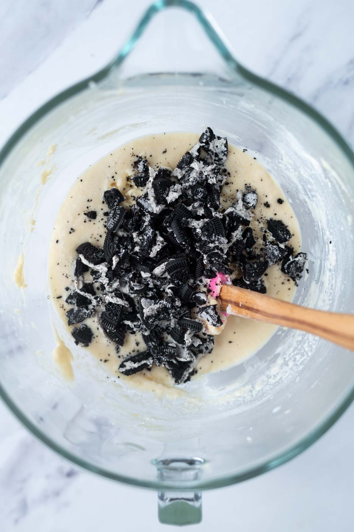 chocolate sandwich cookie pieces over cake batter in a mixing bowl with a spatula