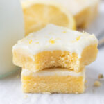 stack of lemon blondies with the top one missing a bite