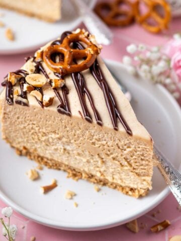 slice of peanut butter pretzel pie on a plate with a fork and a bowl of peanuts and fresh flowers in the background