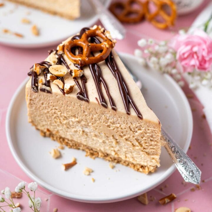 slice of peanut butter pretzel pie on a plate with a fork and a bowl of peanuts and fresh flowers in the background