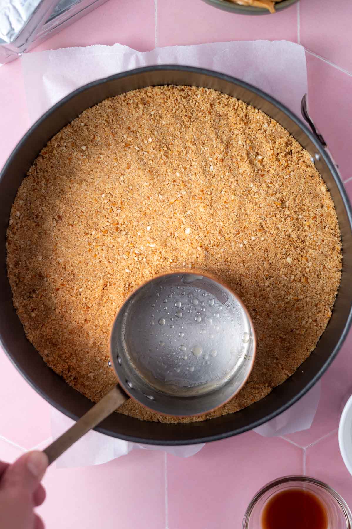 tiny saucepan pressing crust into a springform pan