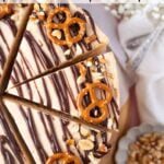 cut slices of peanut butter pretzel pie on a cake stand with flower and utensils in the background with pinterest text overlay