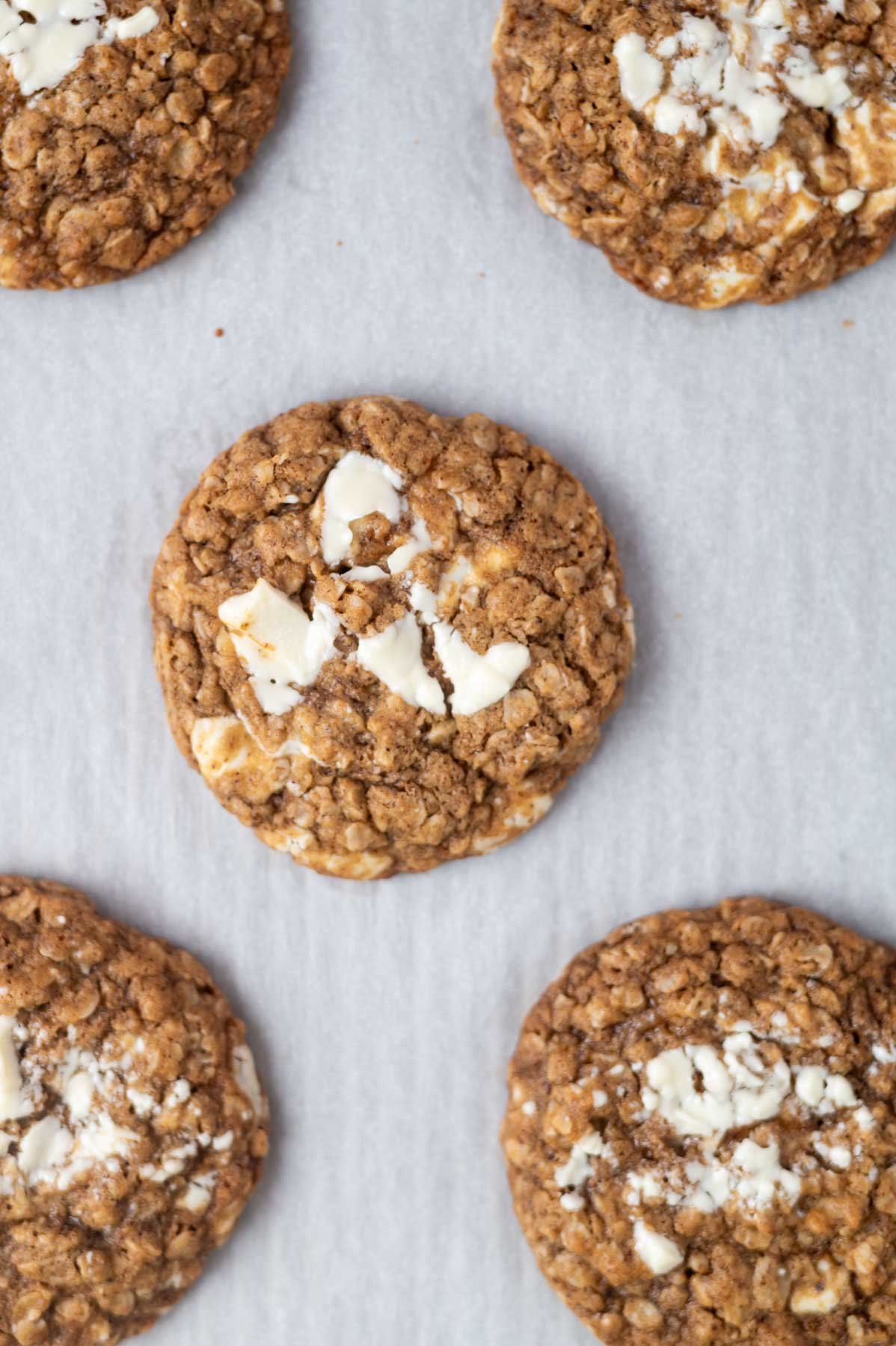 baked cookies on a parchment lined baking sheet showing puddles of melted chocolate