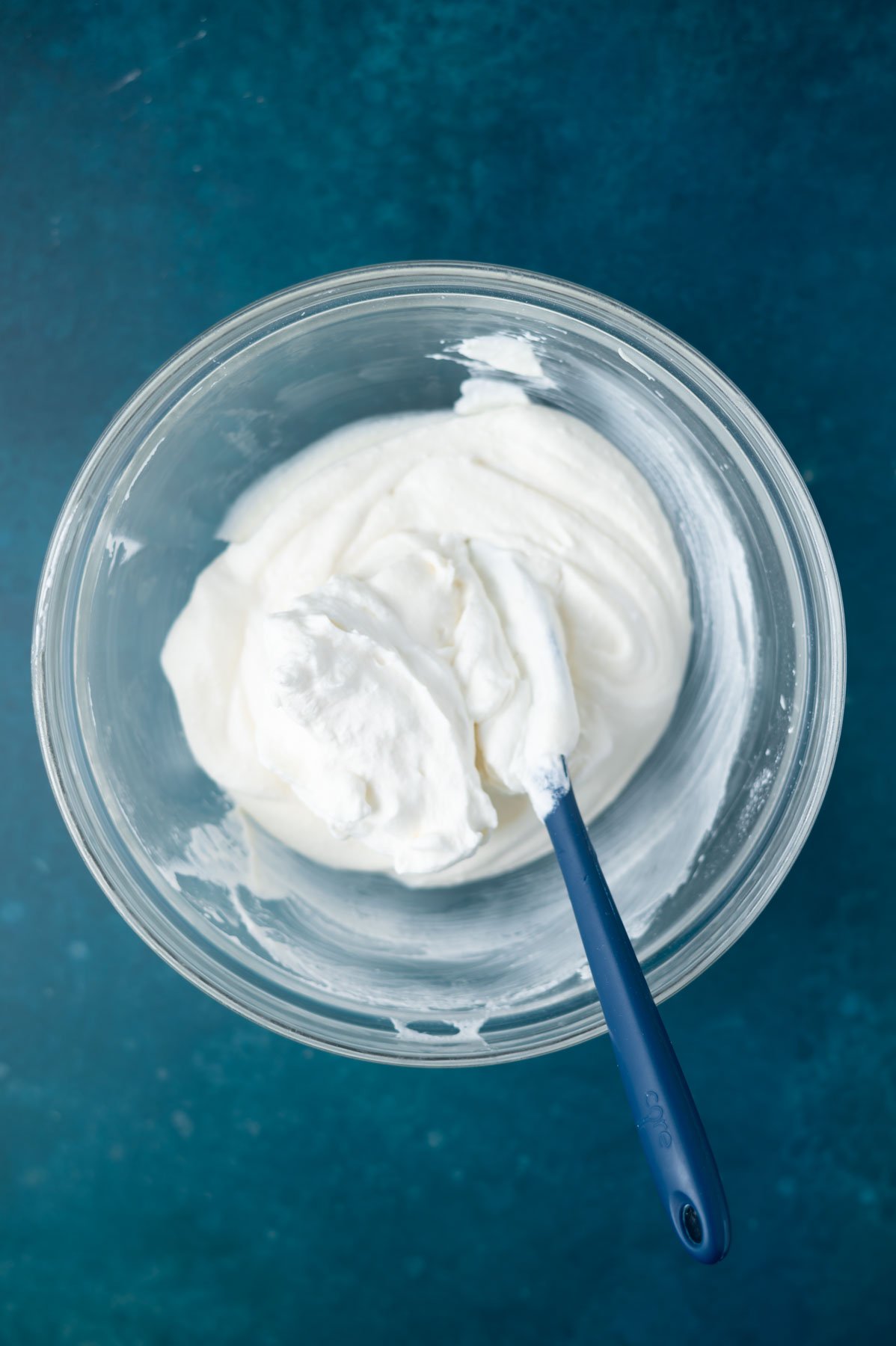 whipped cream added to cannoli filling in a bowl with a spatula