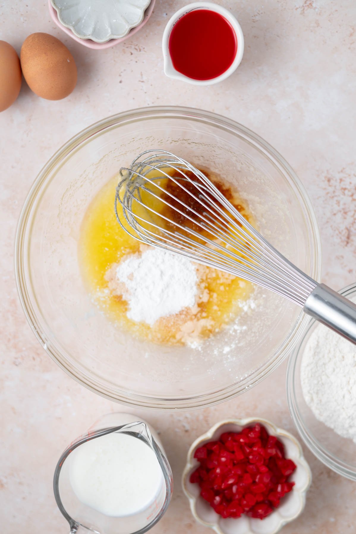 baking powder and vanilla added to melted butter and sugar in a mixing bowl with a whisk