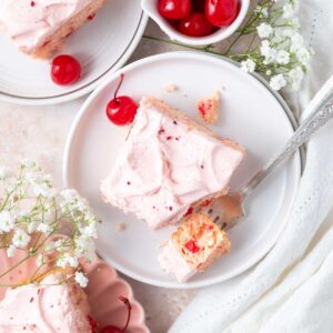 slices of cherry chip cake on a plates with a bite on a fork and a bowl of cherries