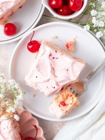slices of cherry chip cake on a plates with a bite on a fork and a bowl of cherries
