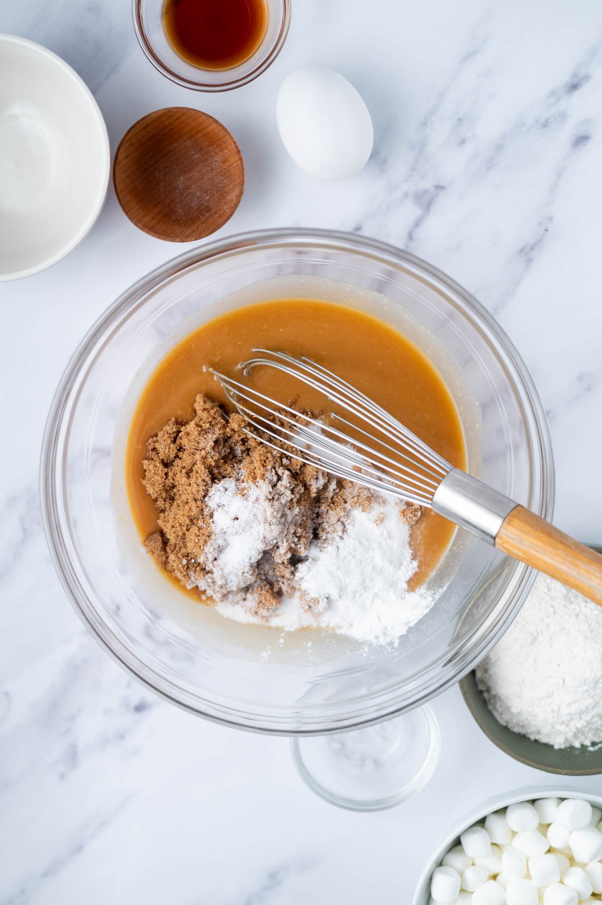brown and granulated sugar added to peanut butter and butter mixture in a bowl with a whisk
