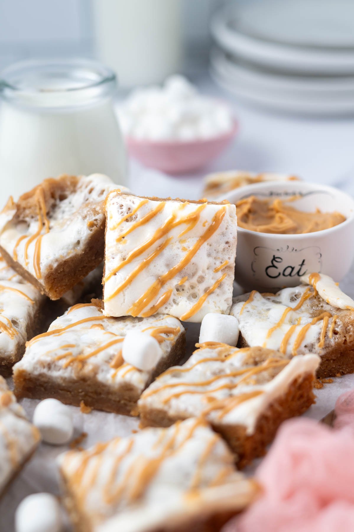 pile of peanut butter fluff bars with bowls of marshmallows, peanut butter and a glass of milk