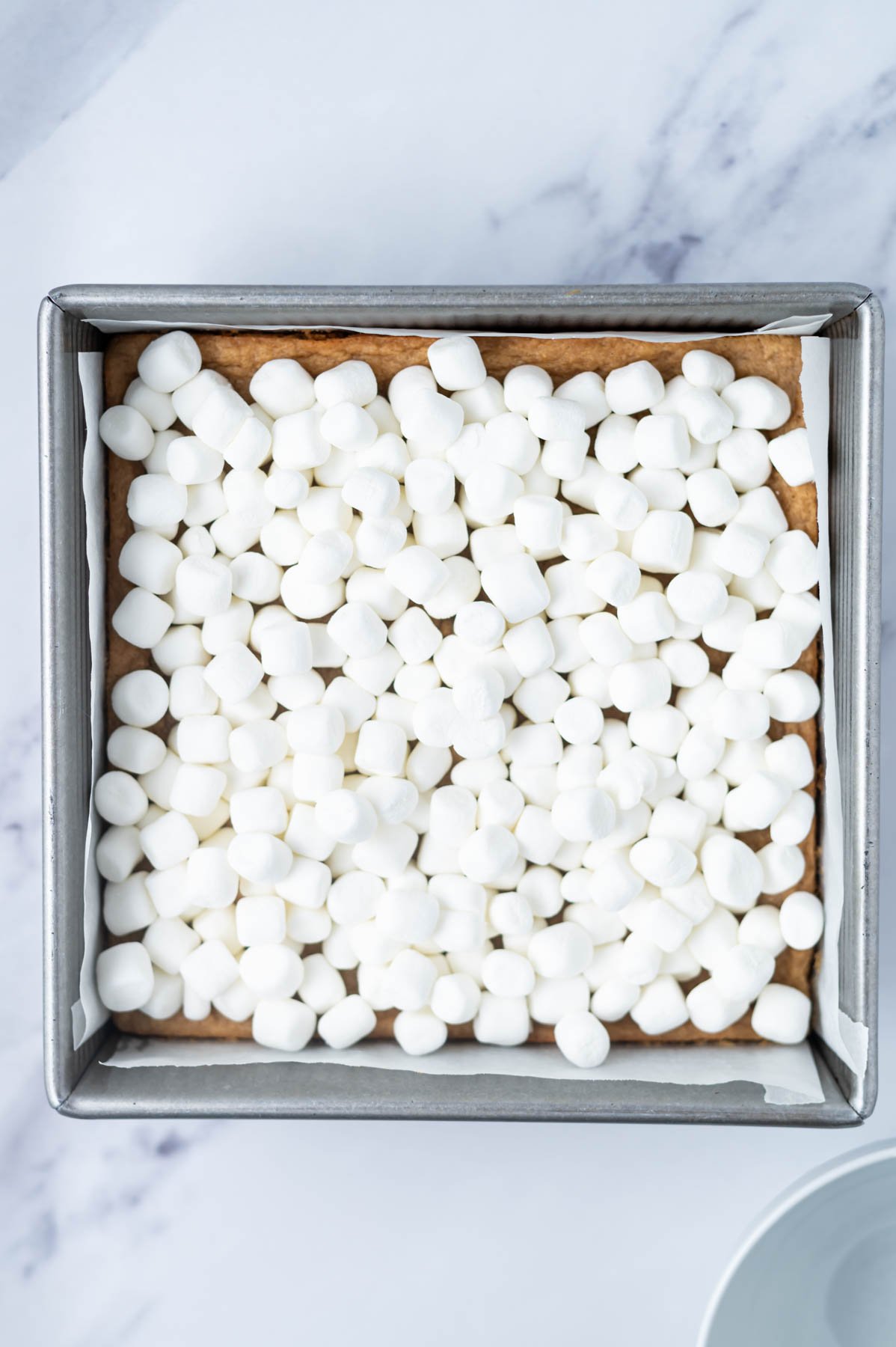 mini marshmallows spead over cookie base in a baking pan