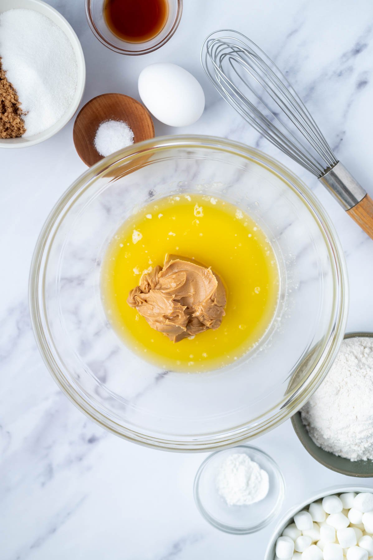 melted butter and peanut butter in a bowl with a whisk and other ingredients in bowls