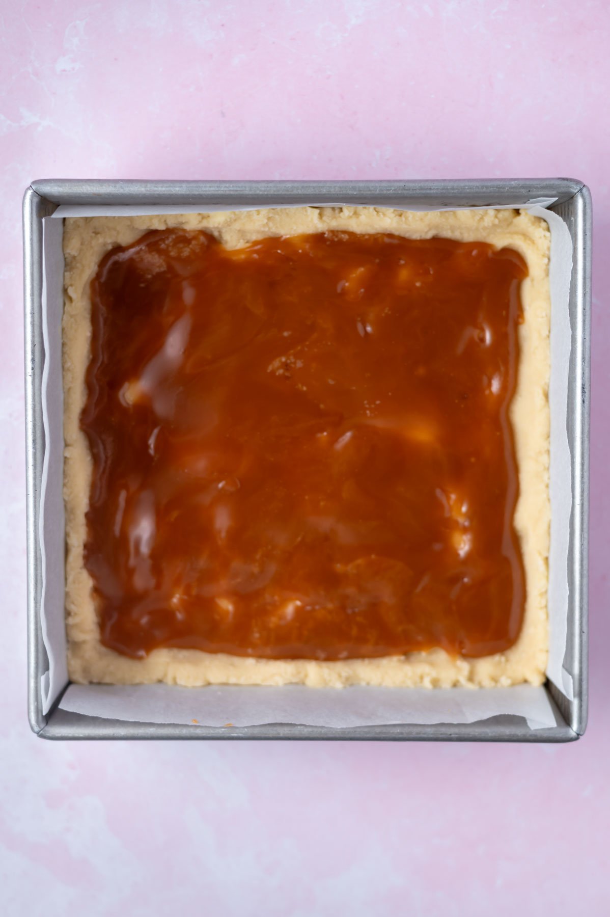 salted caramel sauce spread over shortbread in a baking pan