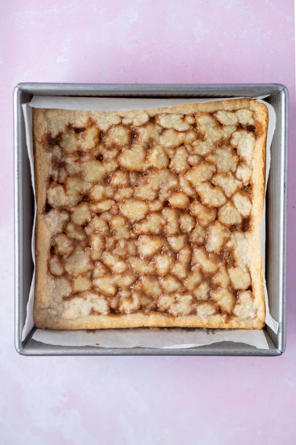 baked caramel cookie bars in a parchment lined 8x8 pan