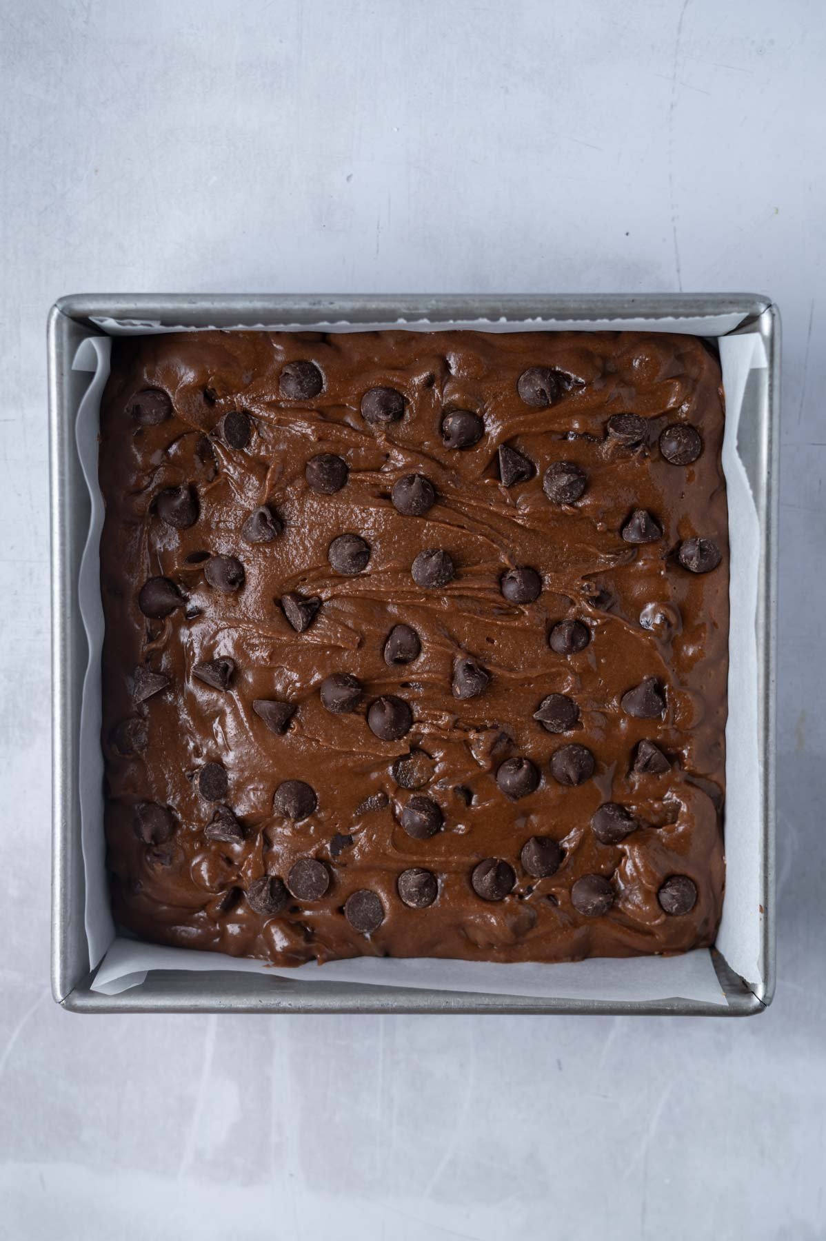 double chocolate cookie bars dough in a parchment lined baking pan