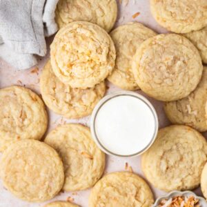 a pile of coconut sugar cookies with a glass of milk