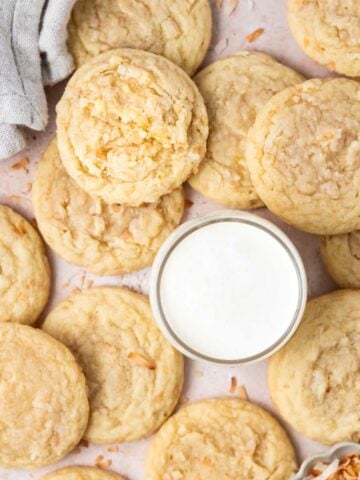 a pile of coconut sugar cookies with a glass of milk