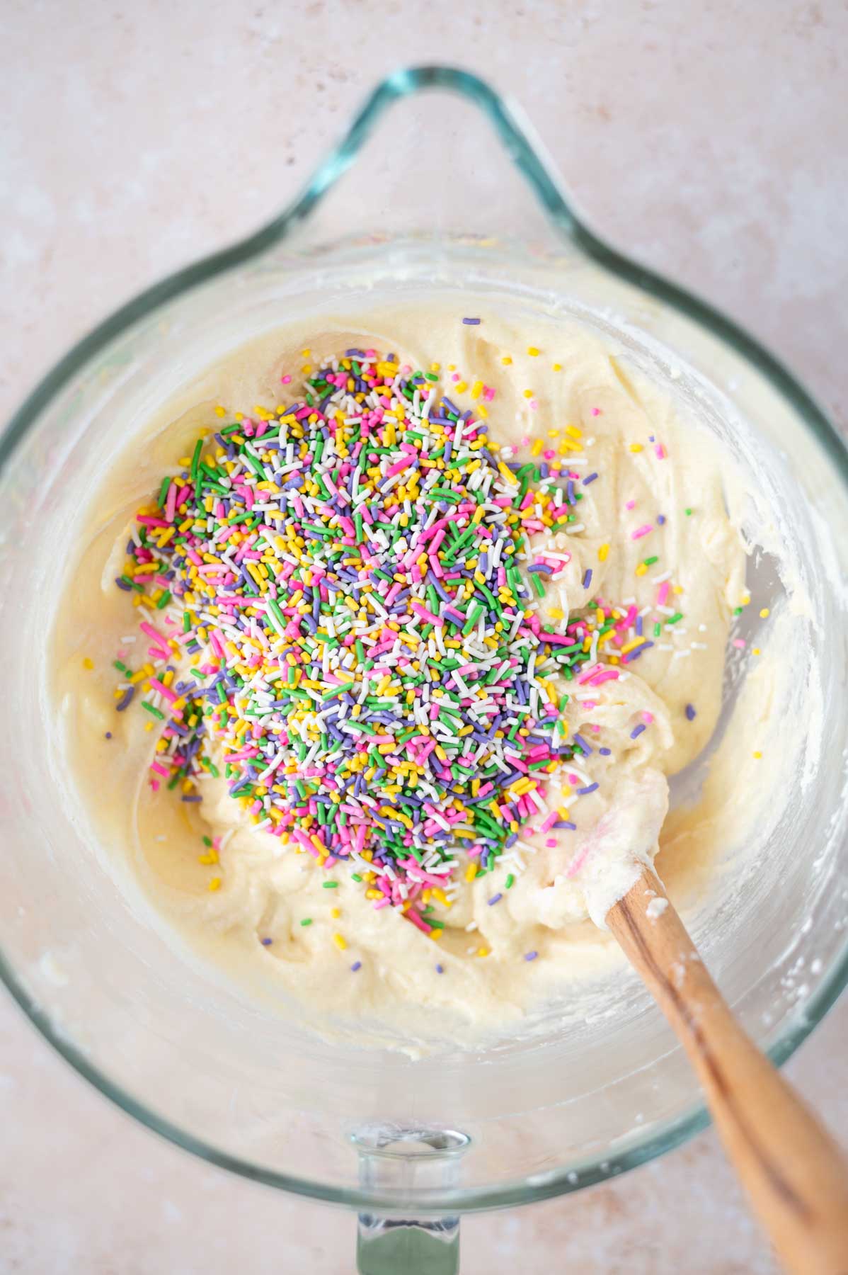 sprinkles added to cake batter in a bowl with a spatula