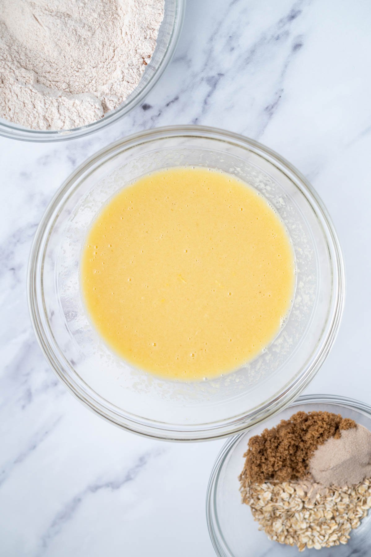 wet ingredients whisked together in a glass bowl with dry ingredients in another bowl