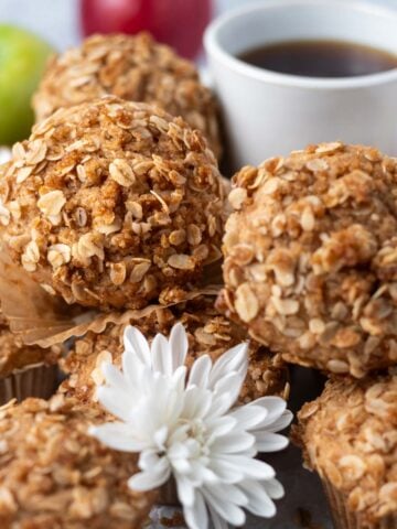 apple cider muffins with streusel on a tray with fresh flours and a cup of coffee