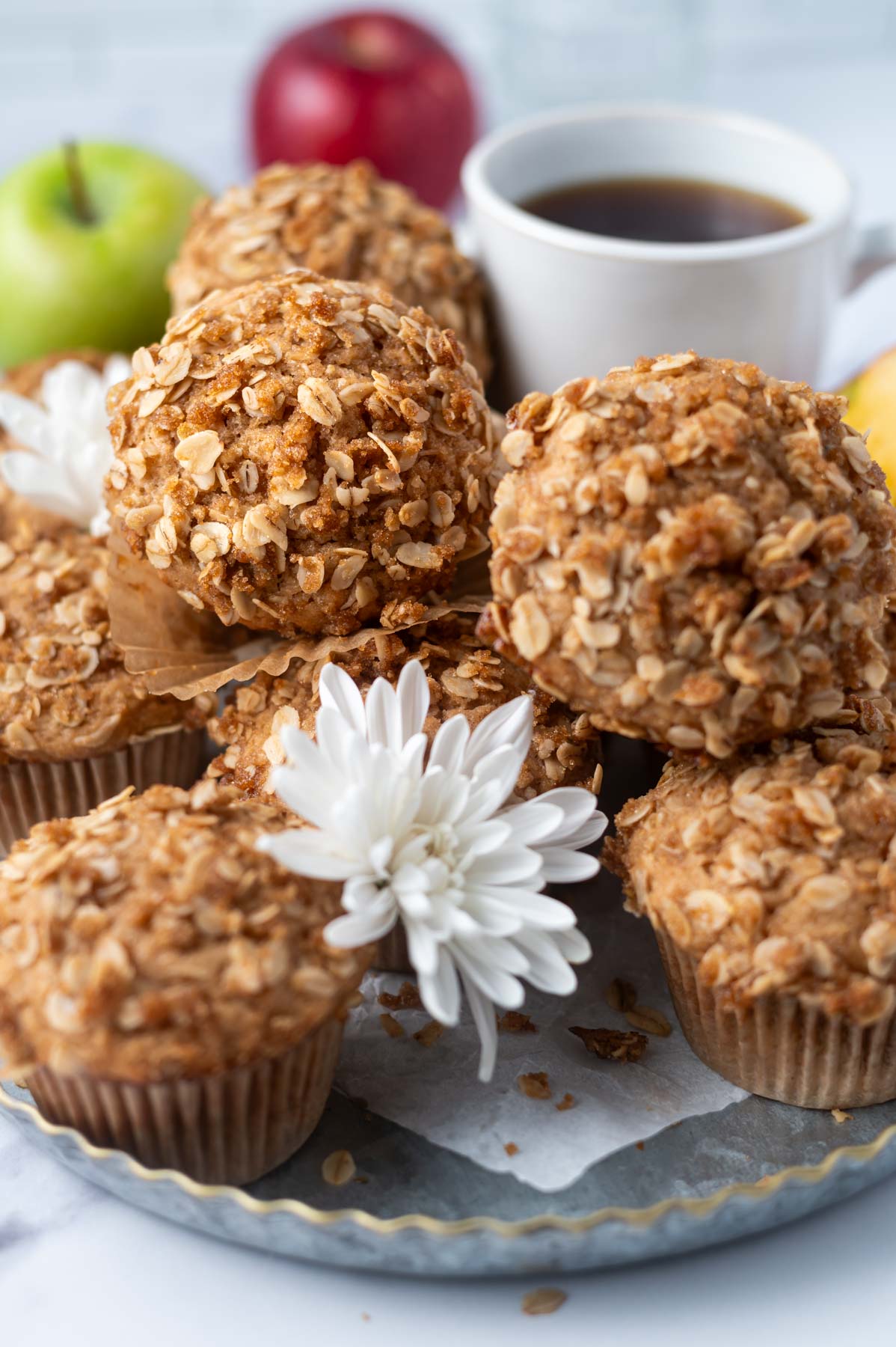 apple cider muffins with streusel on a tray with fresh flours and a cup of coffee