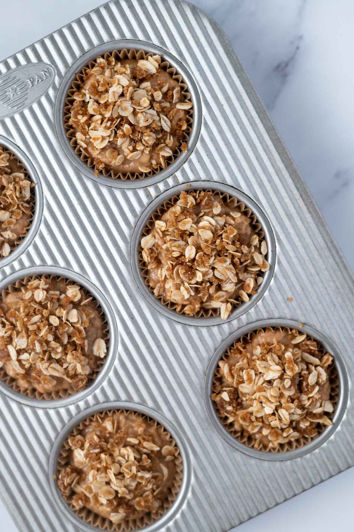 unbaked muffins with streusel in a muffin tin