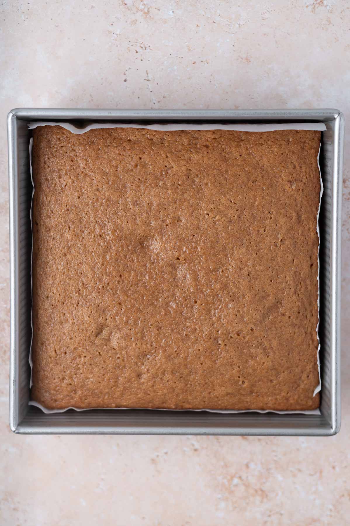 baked cake in a parchment lined 9x9 pan
