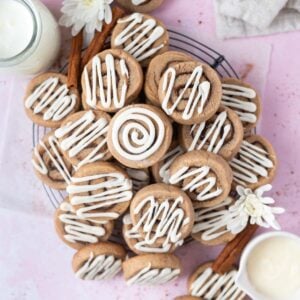 pile of cinnamon roll sugar cookies on a cooling rack with a glass of milk