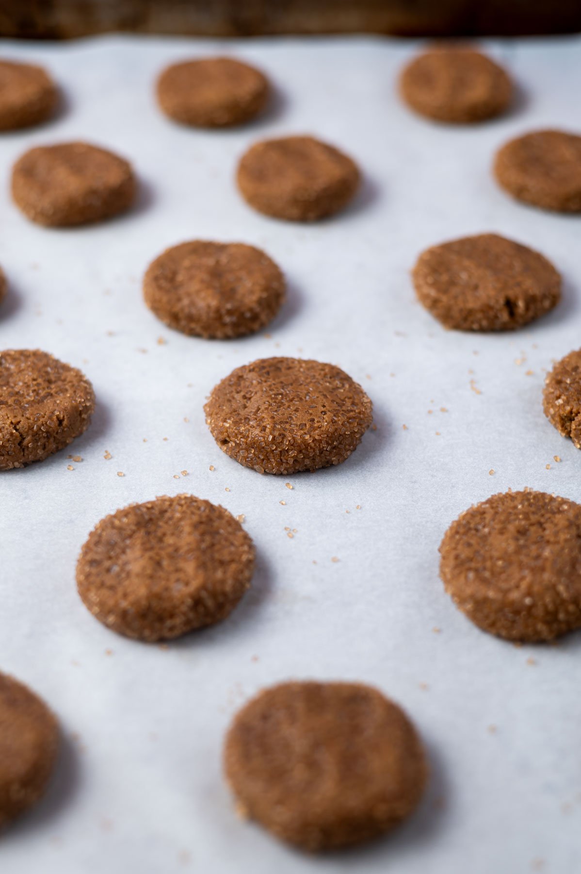 cookie dough balls flattened on a parchment lined baking sheet
