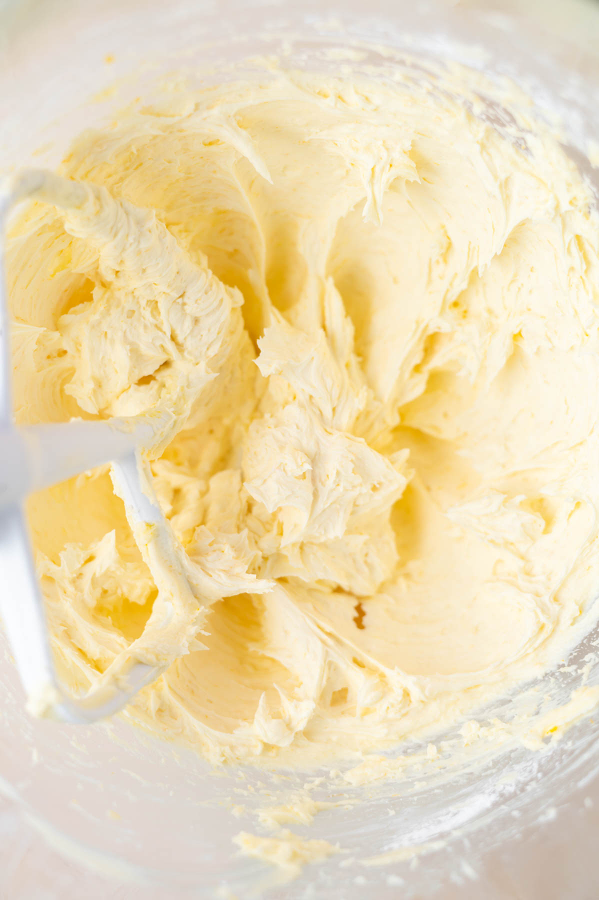 orange buttercream in a mixing bowl with a paddle