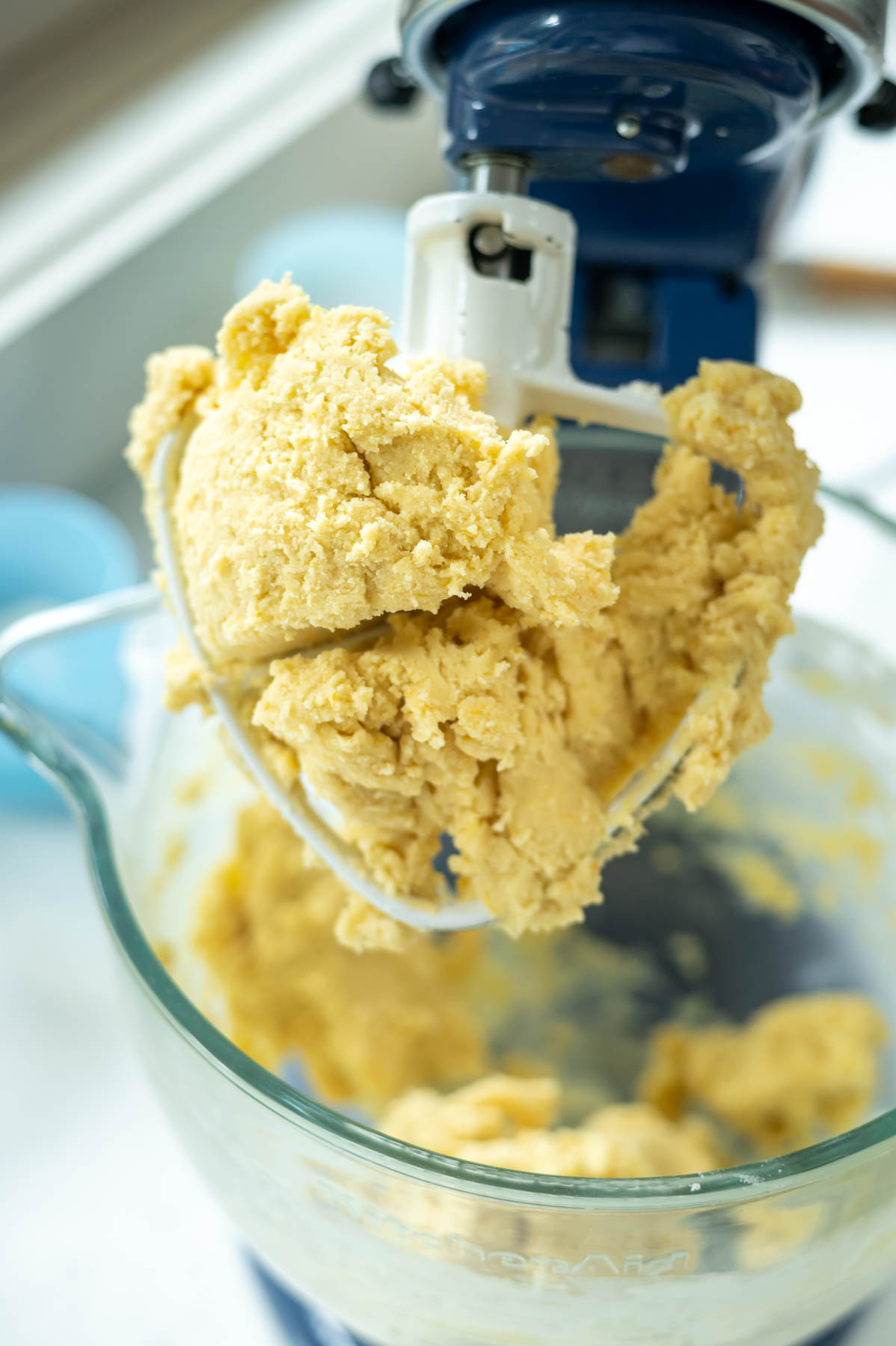 orange sugar cookie dough grabbed into a ball on the paddle of a mixer