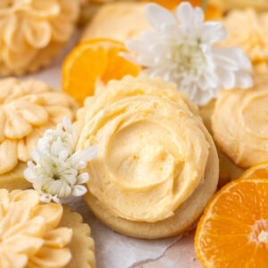 orange sugar cookies with orange slices and flowers on parchment paper