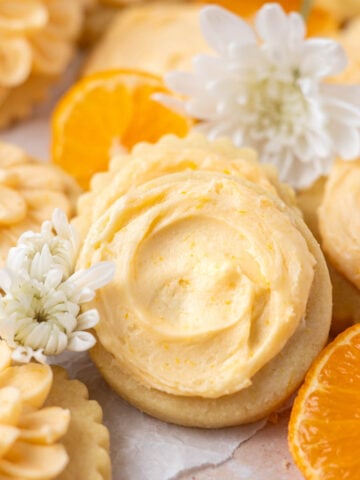 orange sugar cookies with orange slices and flowers on parchment paper