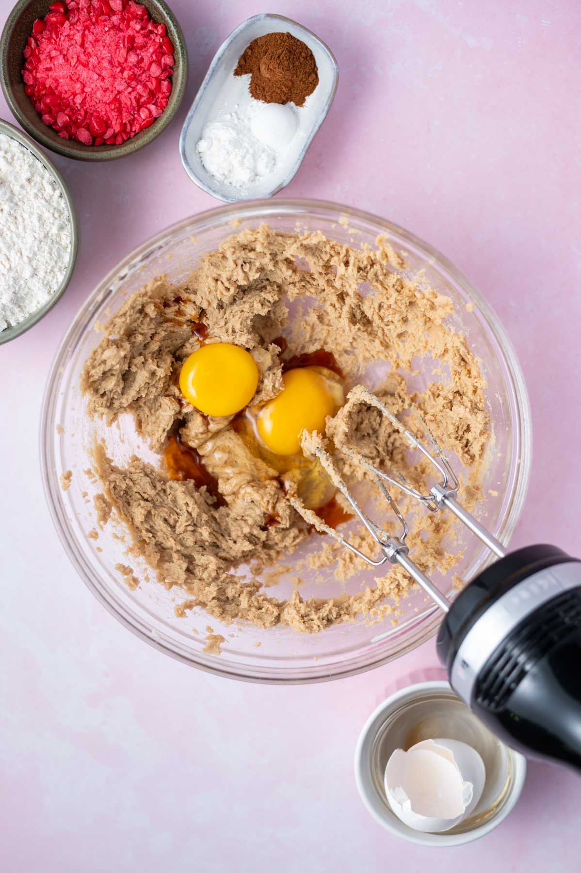 cookie dough in a bowl with eggs and vanilla and a handmixer