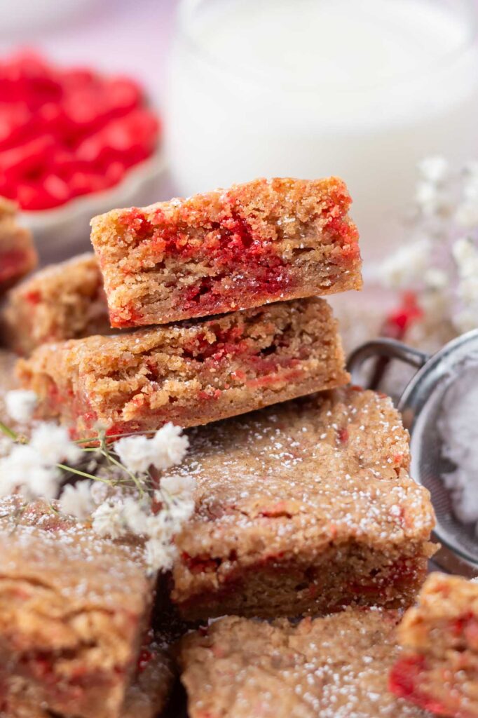 pile of cinnamon blondies with milk and cinnamon candies in the background