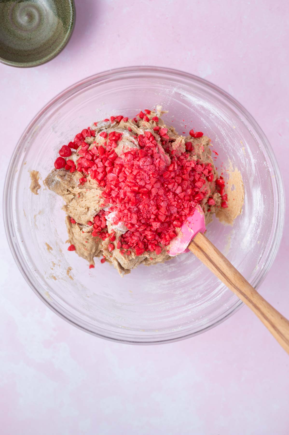 cinnamon candies added to cookie dough in a bowl with a spatula