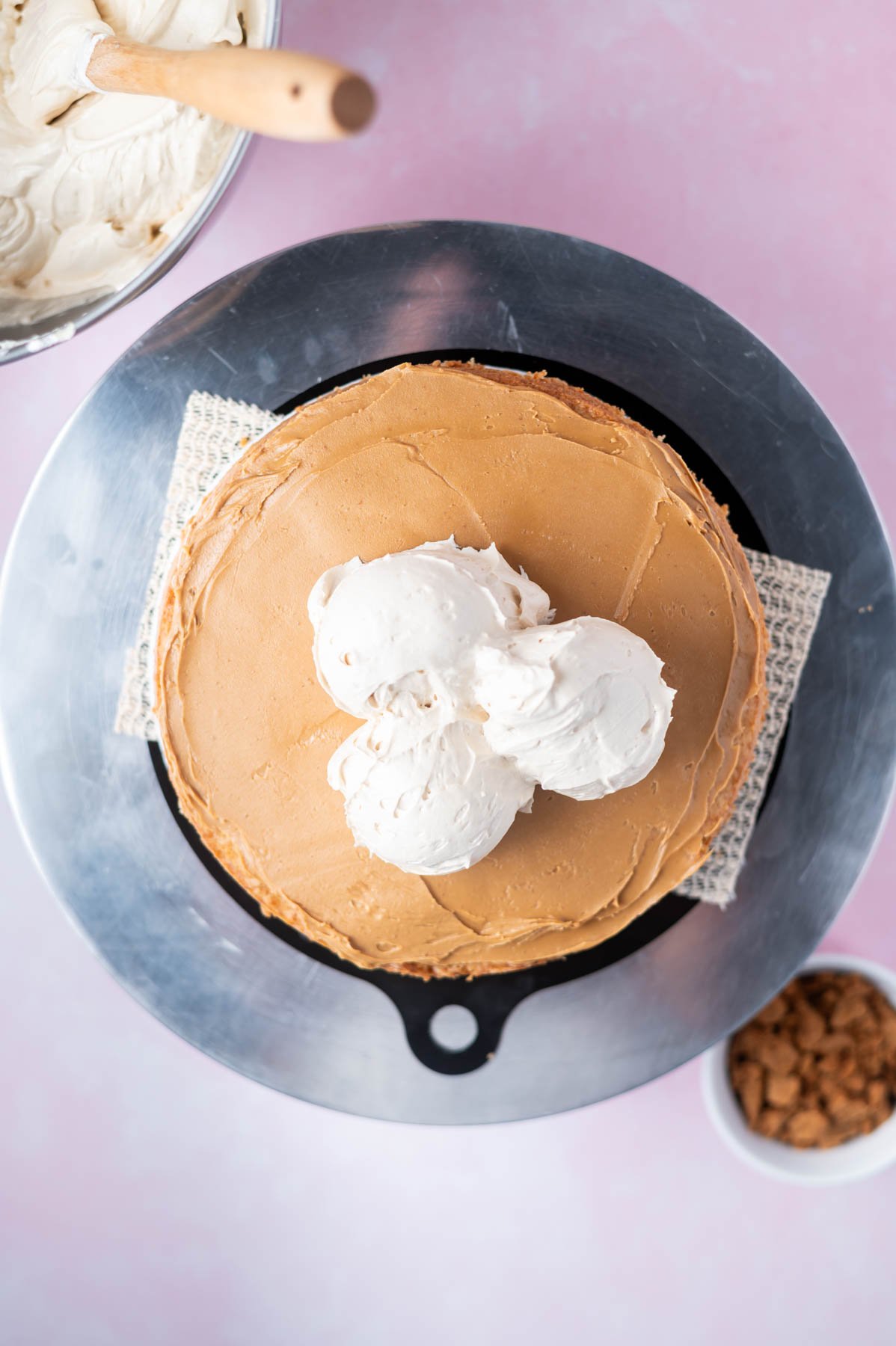 cookie butter and frosting on a cake layer sitting on a turntable